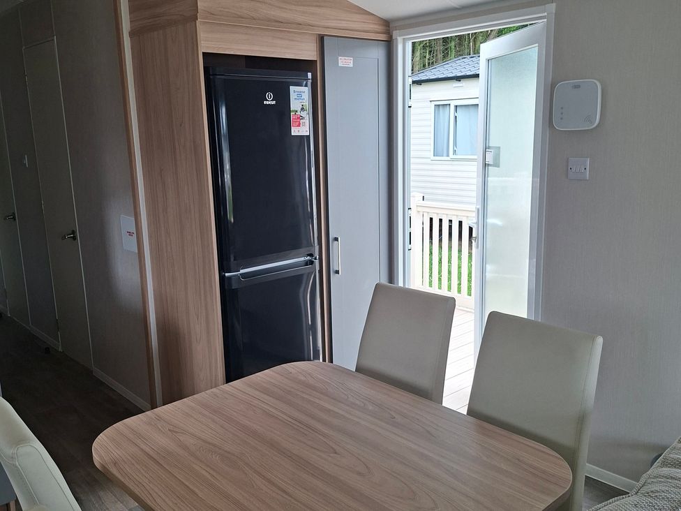 A kitchen with a fridge and table at Primrose Valley, Amara's Retreat in Filey