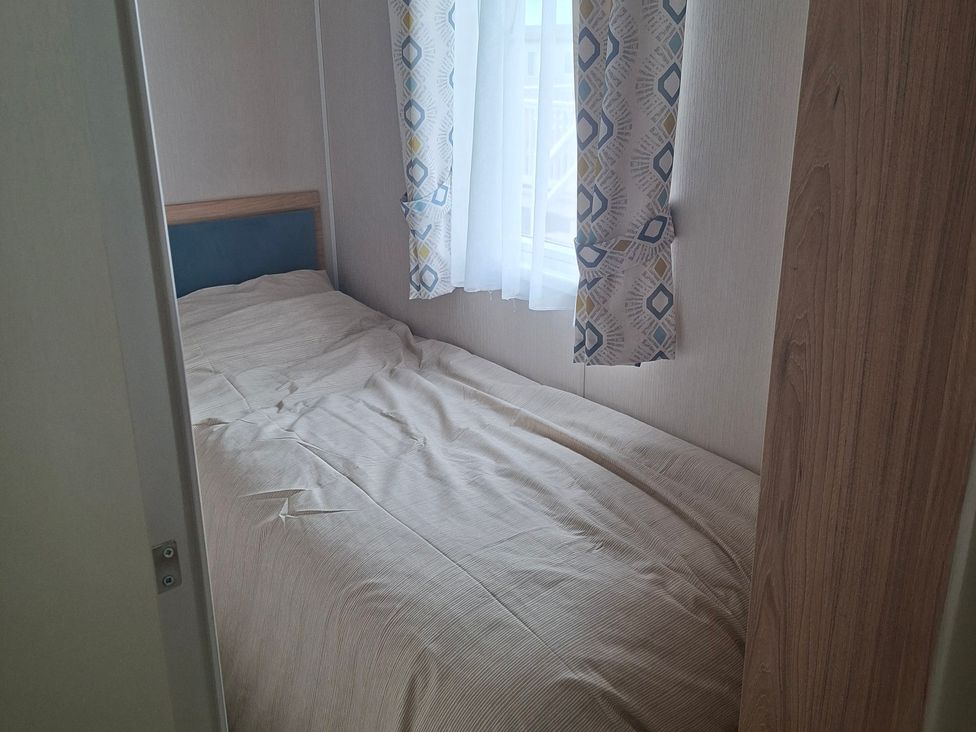 A bedroom with a bed and window at Primrose Valley, Amara's Retreat in Filey
