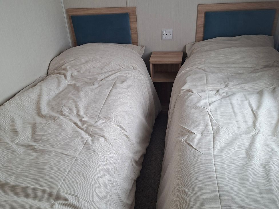 A bedroom with twin beds and a bedside table at Primrose Valley, Amara's Retreat in Filey