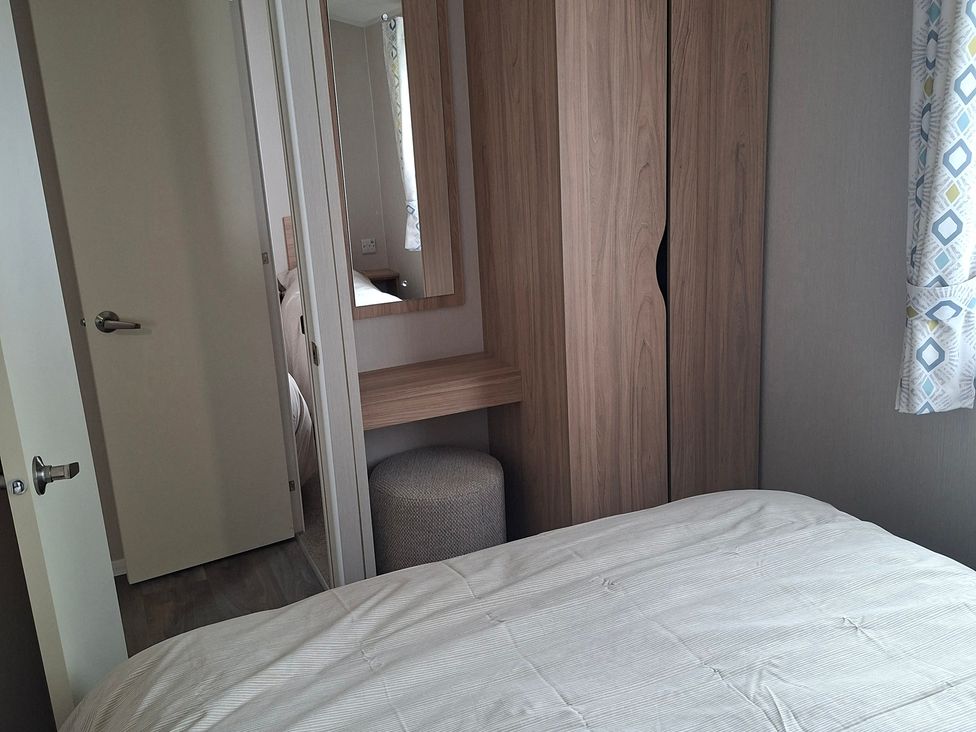 A bedroom with a bed and wardrobe at Primrose Valley, Amara's Retreat in Filey