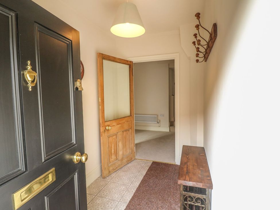 A hallway with a front door and wooden side table at Lion House in Ashbourne