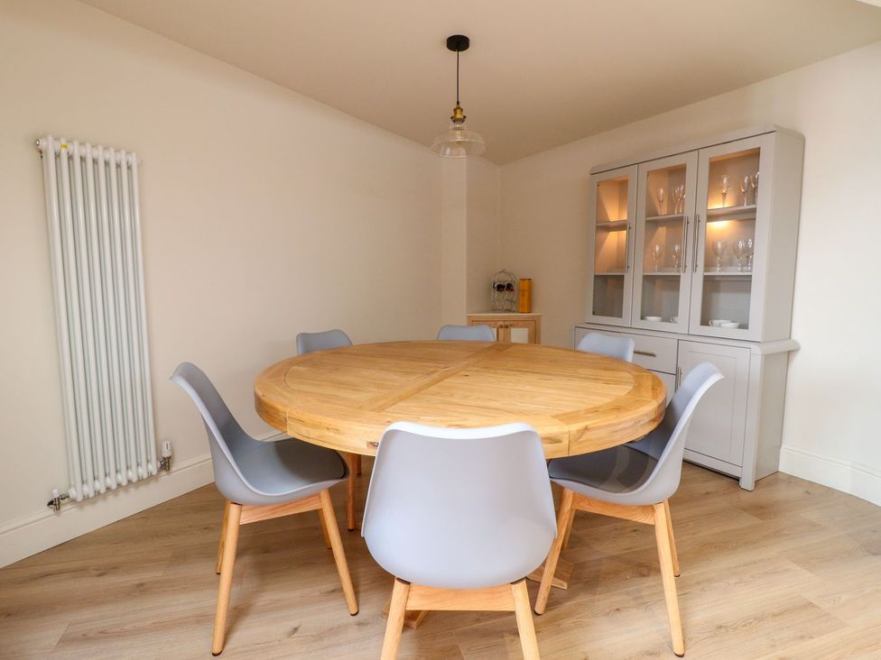 A dining room featuring a round wooden table and grey chairs at Lion House in Ashbourne