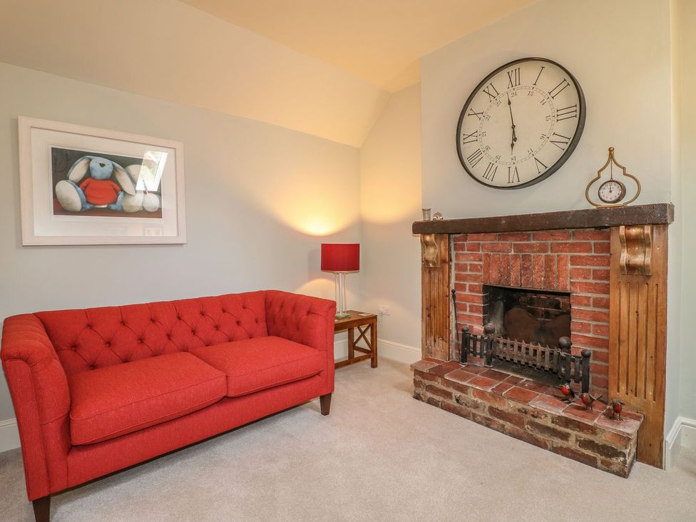 A living room with a red sofa and a fireplace at Lion House Ashbourne