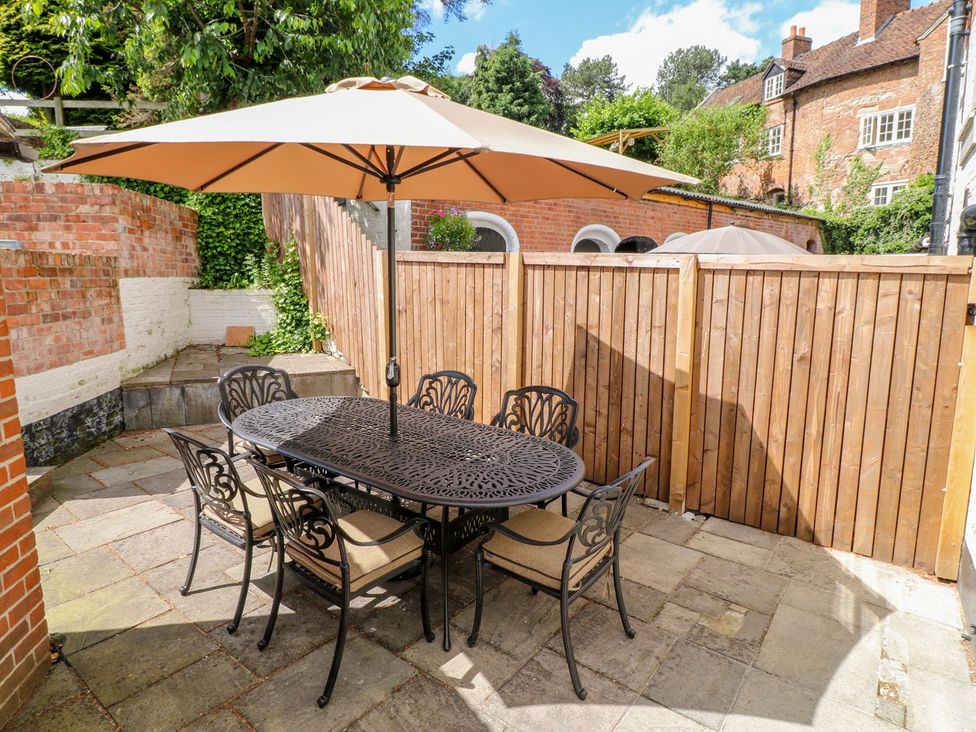 A patio area with a table and chairs under an umbrella at Lion House in Ashbourne