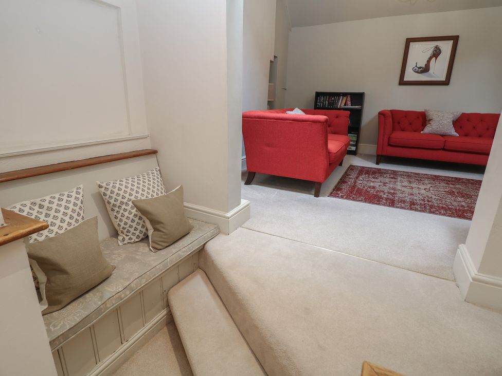 A living room with red sofas and a staircase at Lion House in Ashbourne
