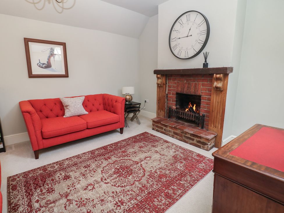 A living room with a red sofa and fireplace at Lion House in Ashbourne