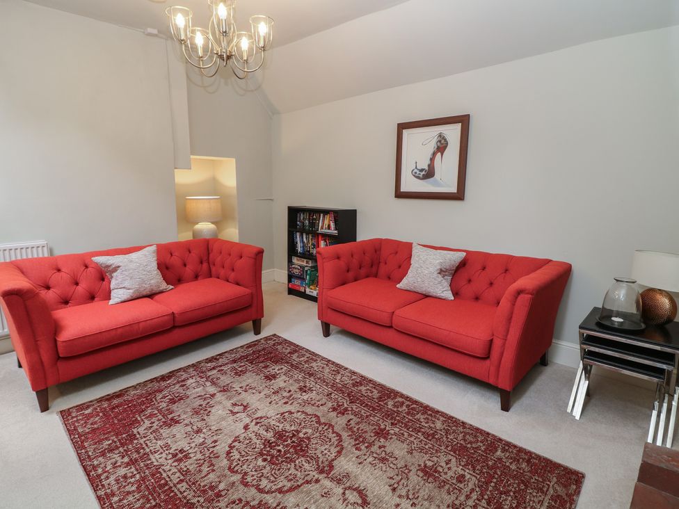A living room with red sofas and a bookshelf at Lion House in Ashbourne