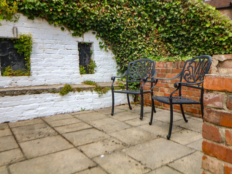 A garden area with two chairs beside a white wall at Lion House Ashbourne