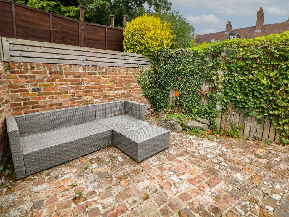 A garden area with a sofa against a brick wall at Lion House, Ashbourne