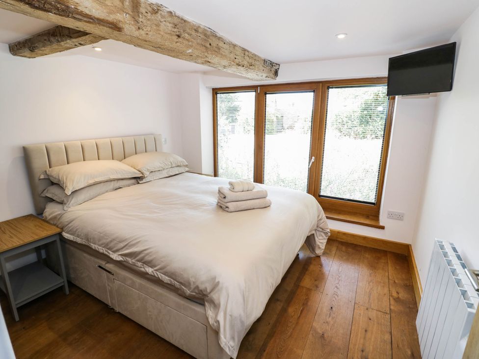 A bedroom with bed and windows at Netherend Barn in Colwall Green near Great Malvern