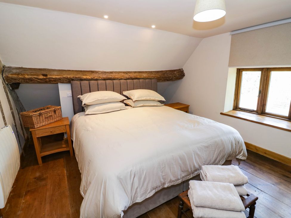 A bedroom with a bed and bedside table at Netherend Barn, Colwall Green near Great Malvern