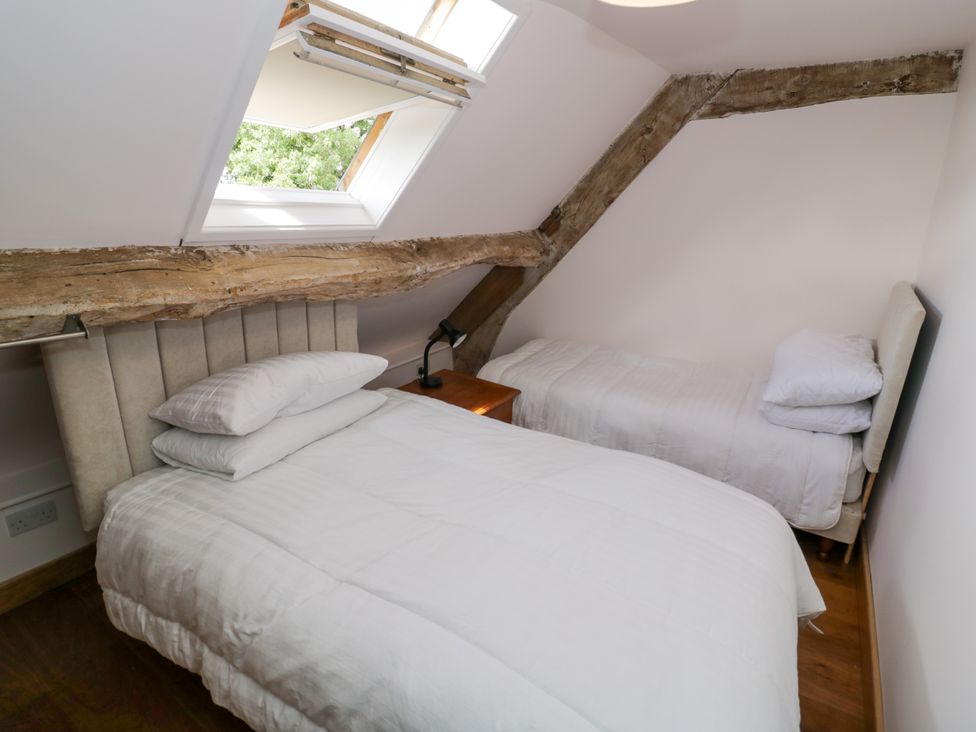 A bedroom featuring two beds and a window at Netherend Barn in Colwall Green near Great Malvern