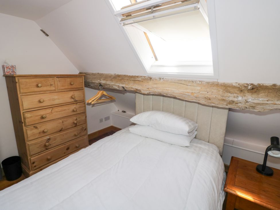 A bedroom with a bed and dresser at Netherend Barn in Colwall Green near Great Malvern