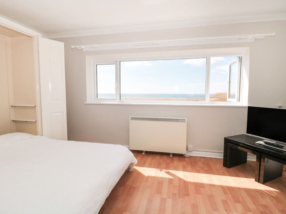 A bedroom with a bed and view of the sea at Flat 30 in Bridport