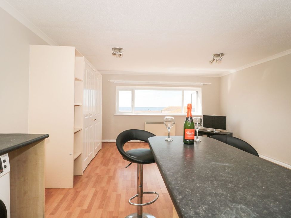 A kitchen with a table and bar stools at Flat 30 in Bridport