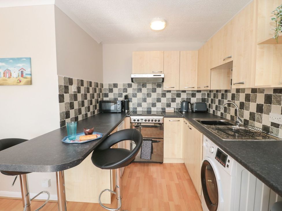 A kitchen with appliances and bar stools at Flat 30 in Bridport