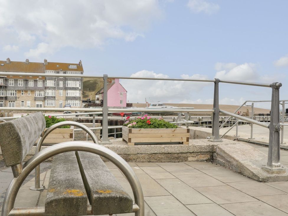 An outdoor seating area with a bench and flowers at Flat 30 in Bridport