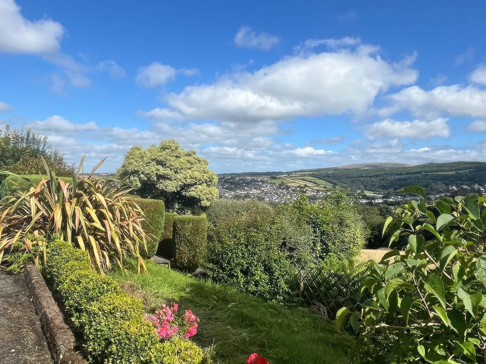 A garden with flowers and trees overlooking a valley at The White House Okehampton