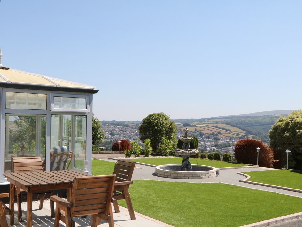 A garden with a conservatory and an outdoor table at The White House in Okehampton