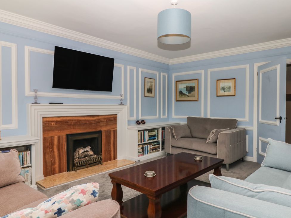 A living room with a television above a fireplace at The White House in Okehampton