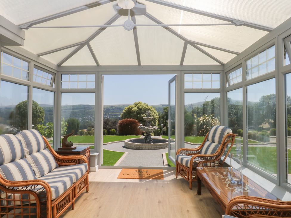 A conservatory with seating and a view of a garden at The White House Okehampton