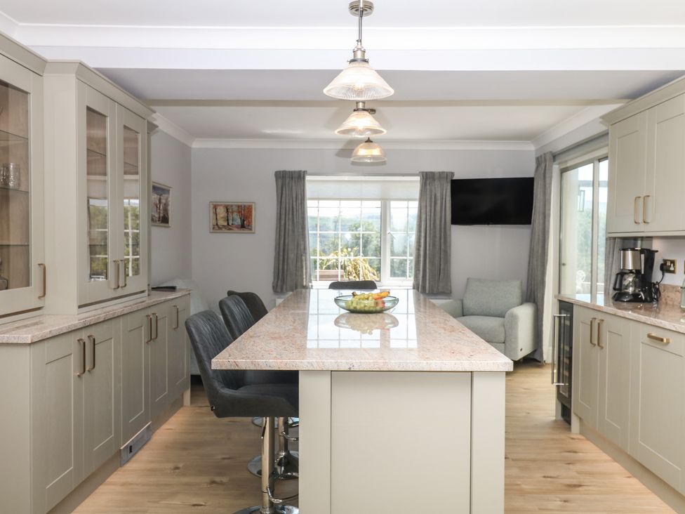 A kitchen with an island counter and bar stools at The White House in Okehampton