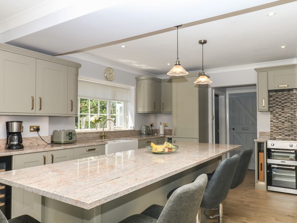 A kitchen with cabinets, island, appliances and stools at The White House in Okehampton