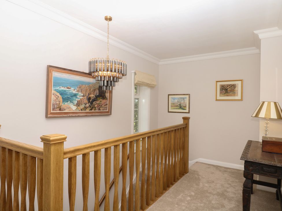 A hallway with a chandelier and paintings at The White House in Okehampton