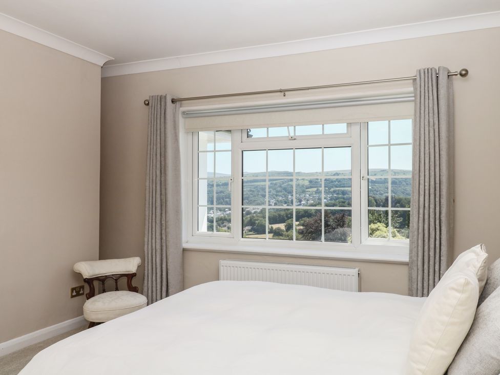 A bedroom with a bed, window, and chair at The White House in Okehampton