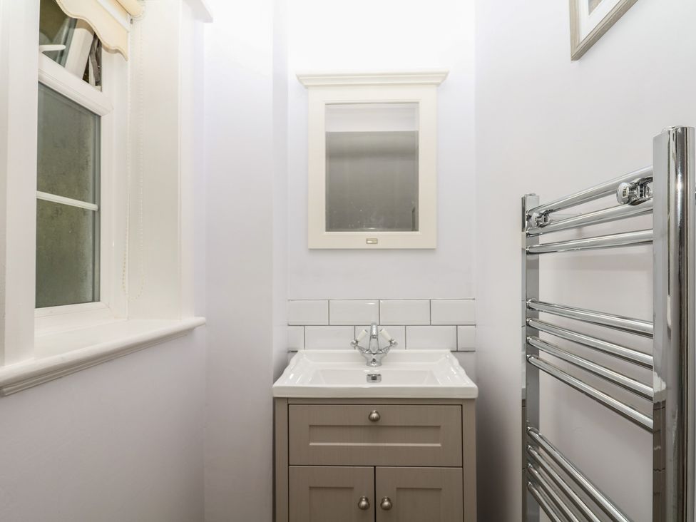 A bathroom with a sink, mirror, and towel radiator at The White House Okehampton