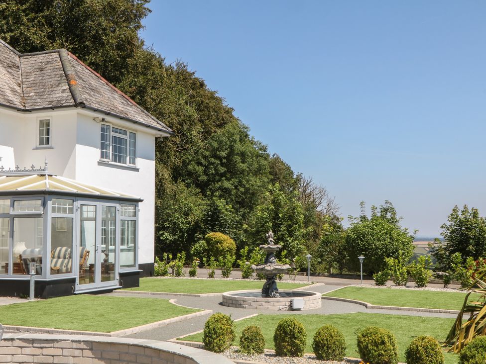 A house with a conservatory and fountain in the garden at The White House Okehampton