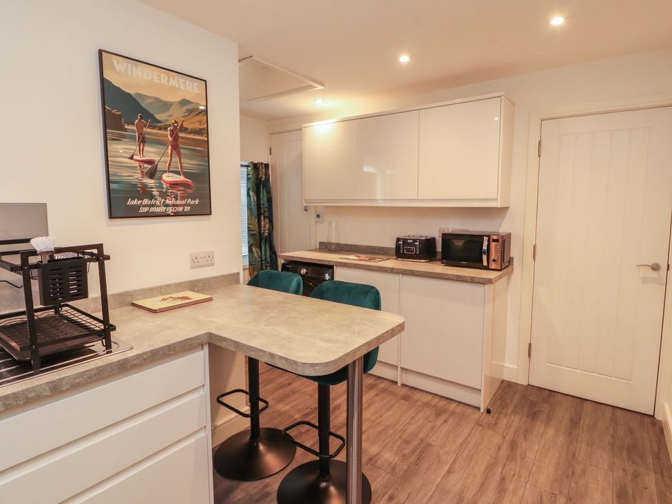 A kitchen with bar stools and kitchen appliances at Hidden Gem