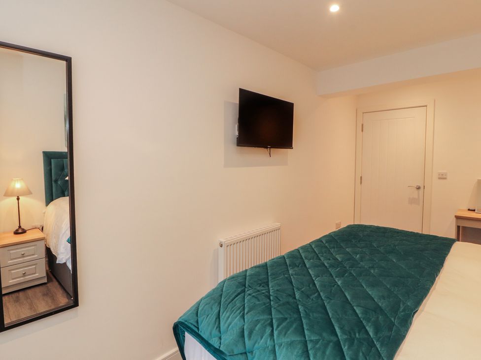 A bedroom with a bed, television, and lamp at Hidden Gem