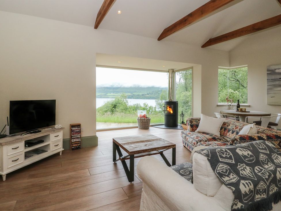 A living room with a television and wood stove at The Tractor Shed in Killin