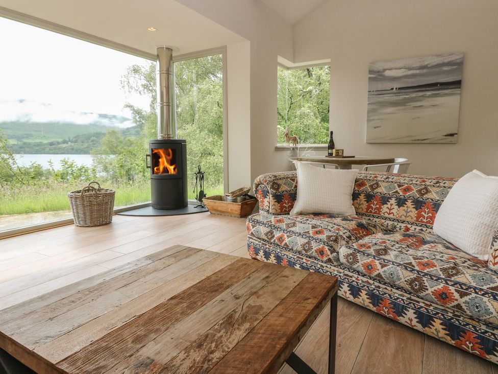A living room with a wood stove and sofa at The Tractor Shed in Killin