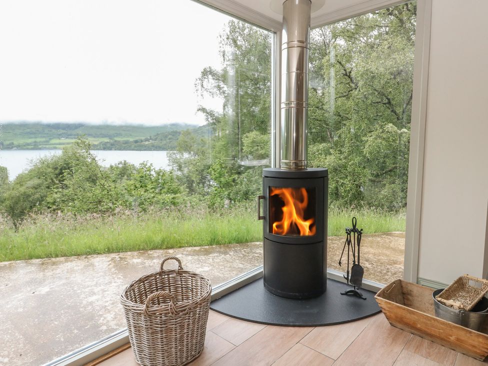 A living room with a wood stove and view of the lake at The Tractor Shed in Killin