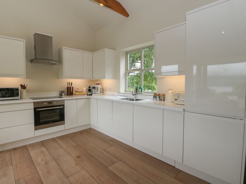 A kitchen with white cabinets and appliances at The Tractor Shed in Killin