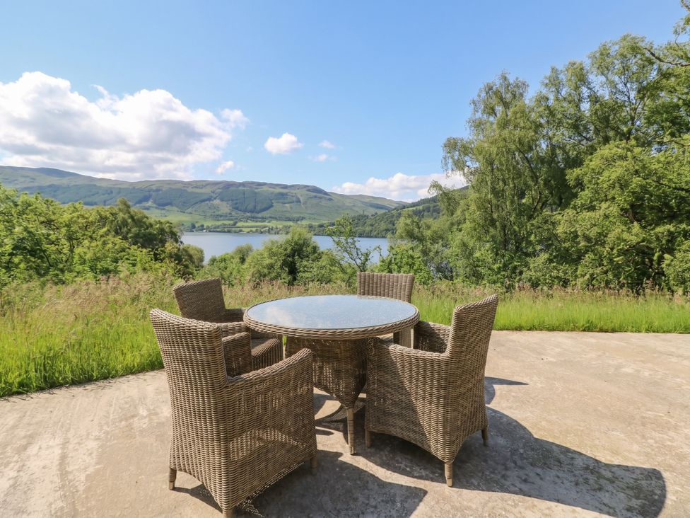 A patio with a table and chairs overlooking the lake at The Tractor Shed in Killin