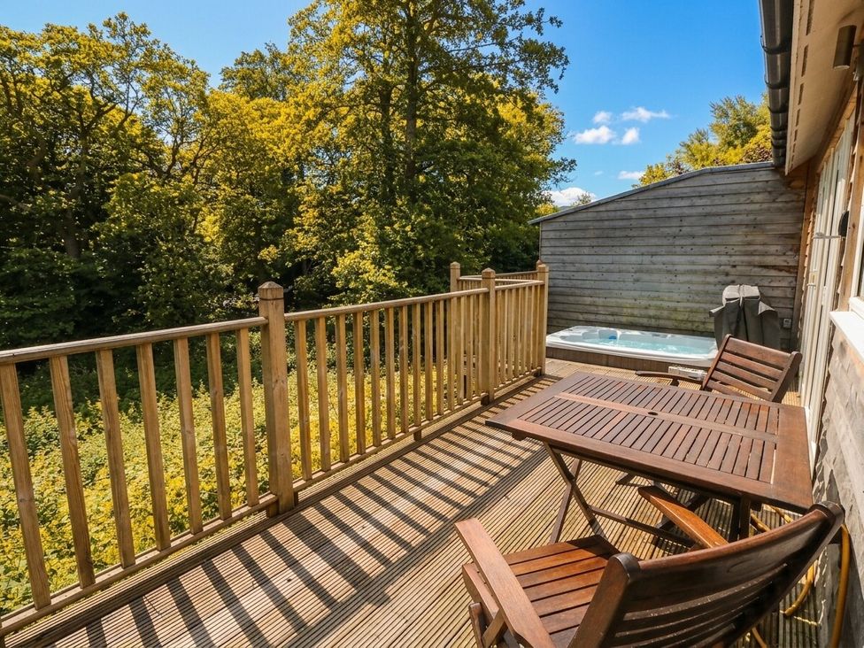 An outdoor deck with a hot tub and seating at Garth Cottage in Killin