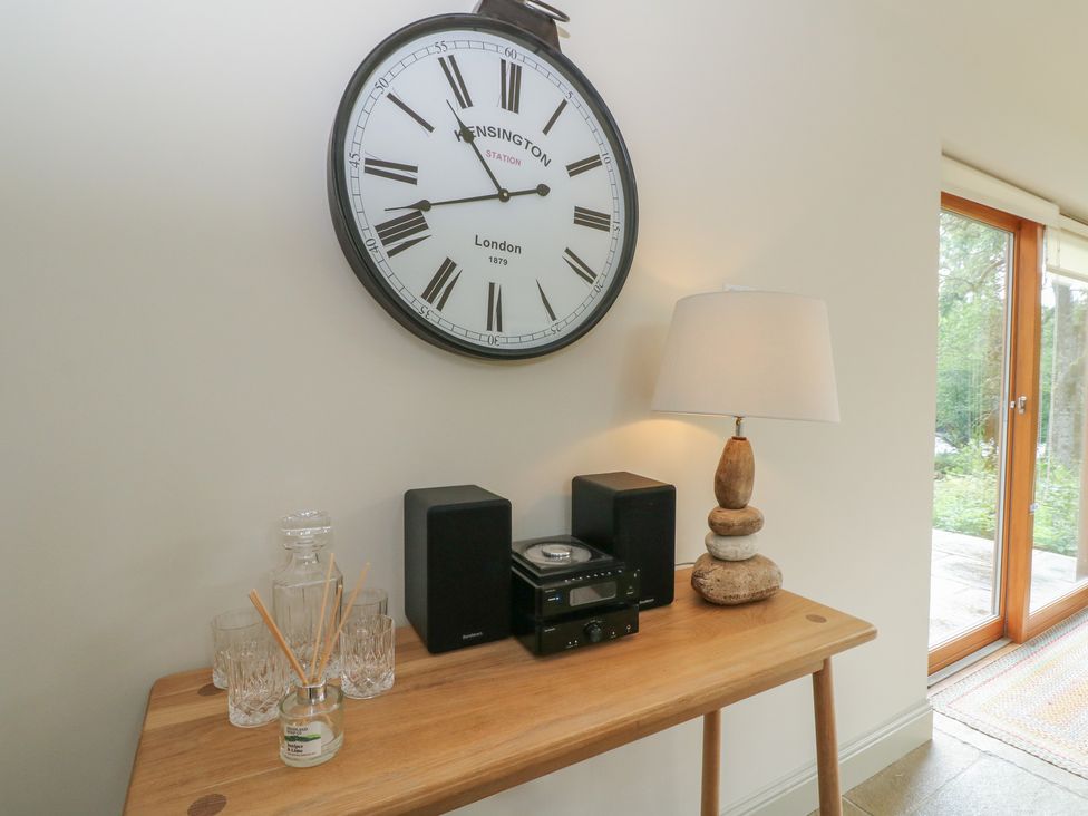 A living room with a clock, table, stereo system, and lamp at Yew Tree in Killin