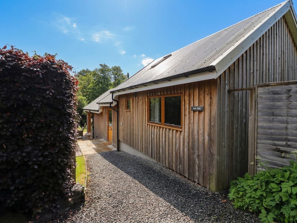 A wooden house with a pathway and plants at Yew Tree in Killin