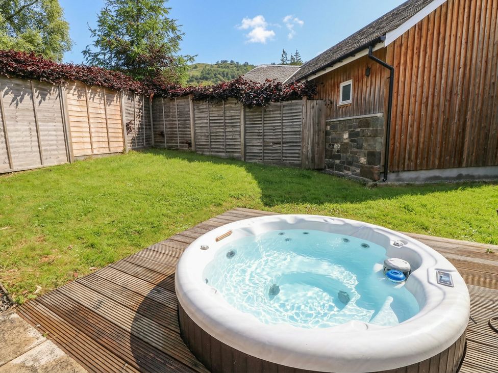 A hot tub on a wooden deck in a garden at Yew Tree in Killin