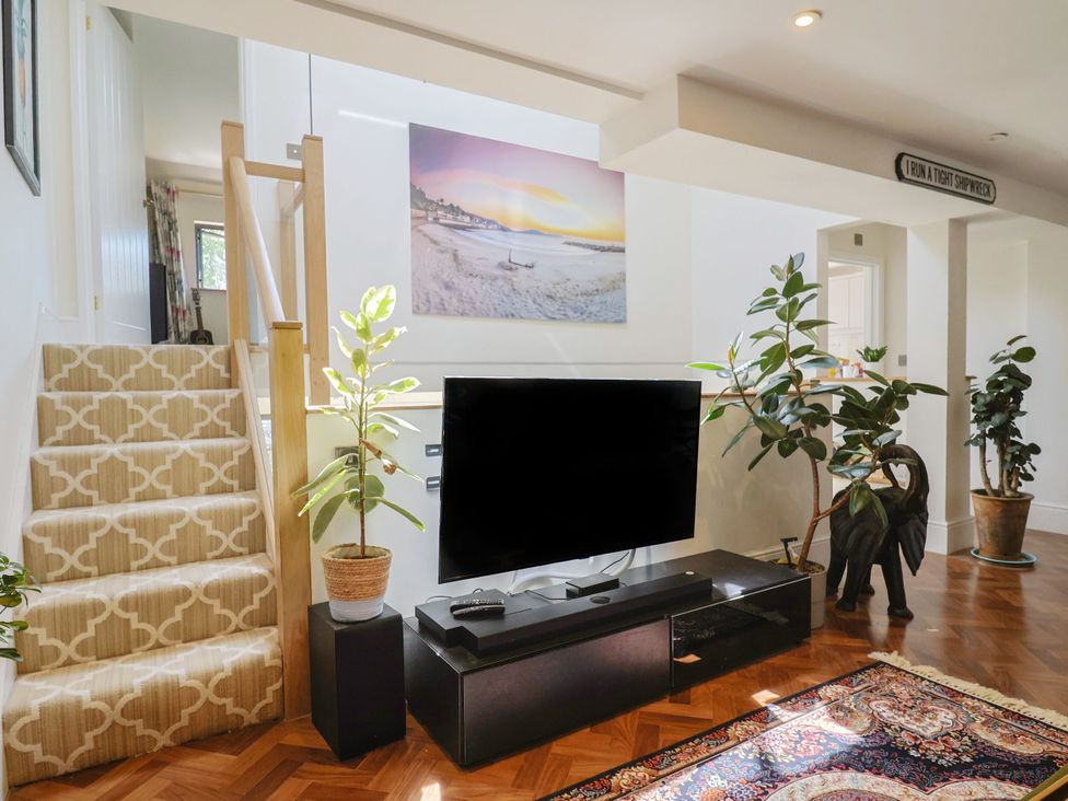 A living room with a television and stairs at Mayflower Cottage Lyme Regis