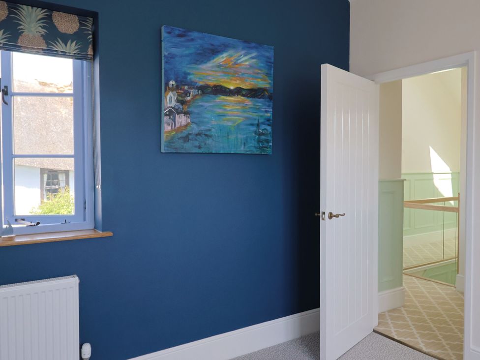 A bedroom with a blue wall and a window at Mayflower Cottage in Lyme Regis