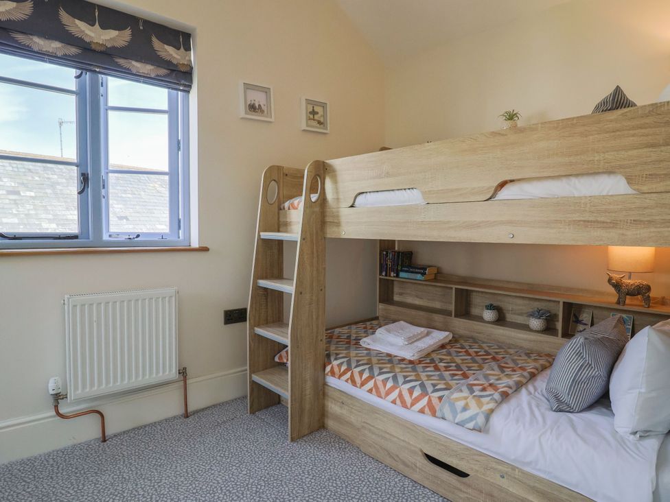 A bedroom with a bunk bed and bookshelf at Mayflower Cottage in Lyme Regis