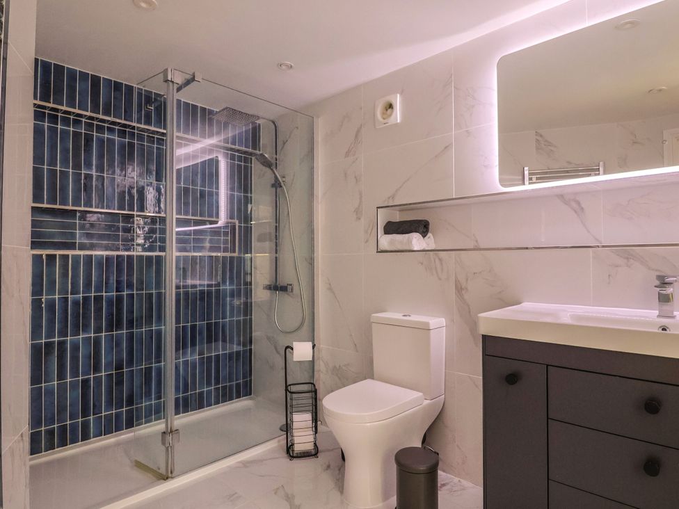 A bathroom with a shower, toilet, sink, and towels at Mayflower Cottage in Lyme Regis