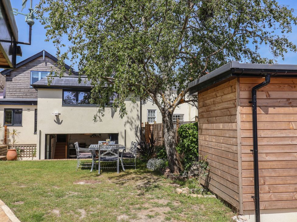 A garden with a table and chairs next to a shed at Mayflower Cottage in Lyme Regis