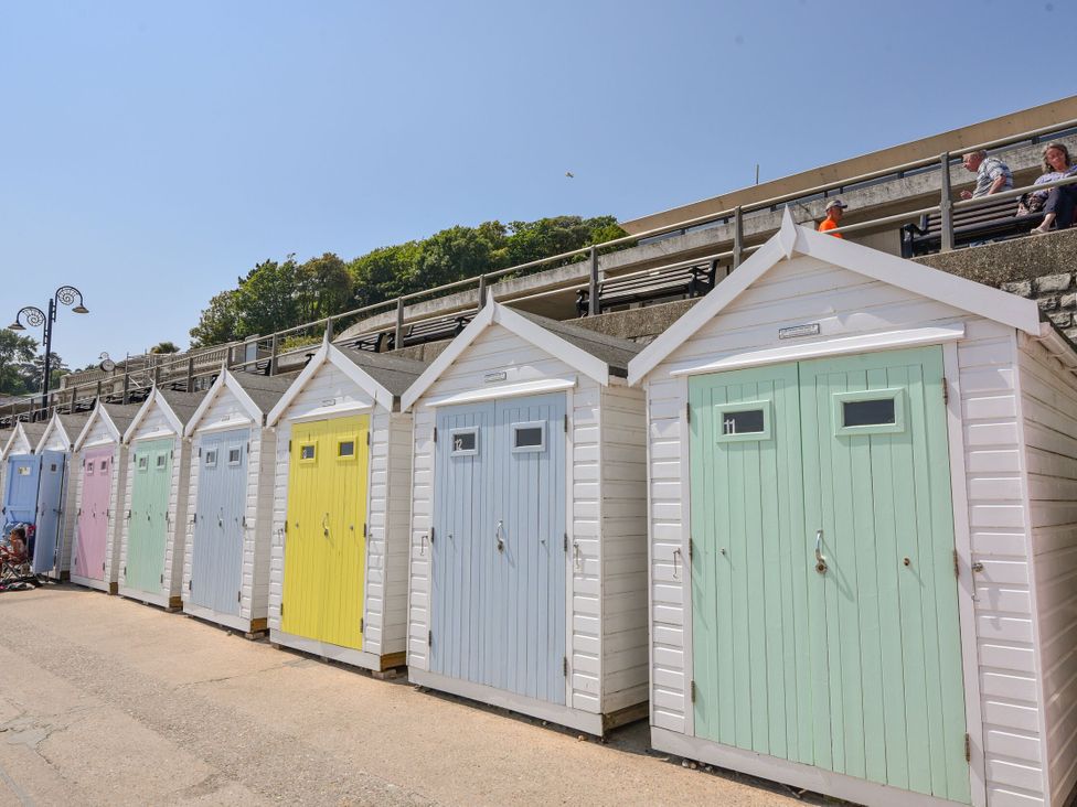A row of beach huts and benches at Mayflower Cottage in Lyme Regis