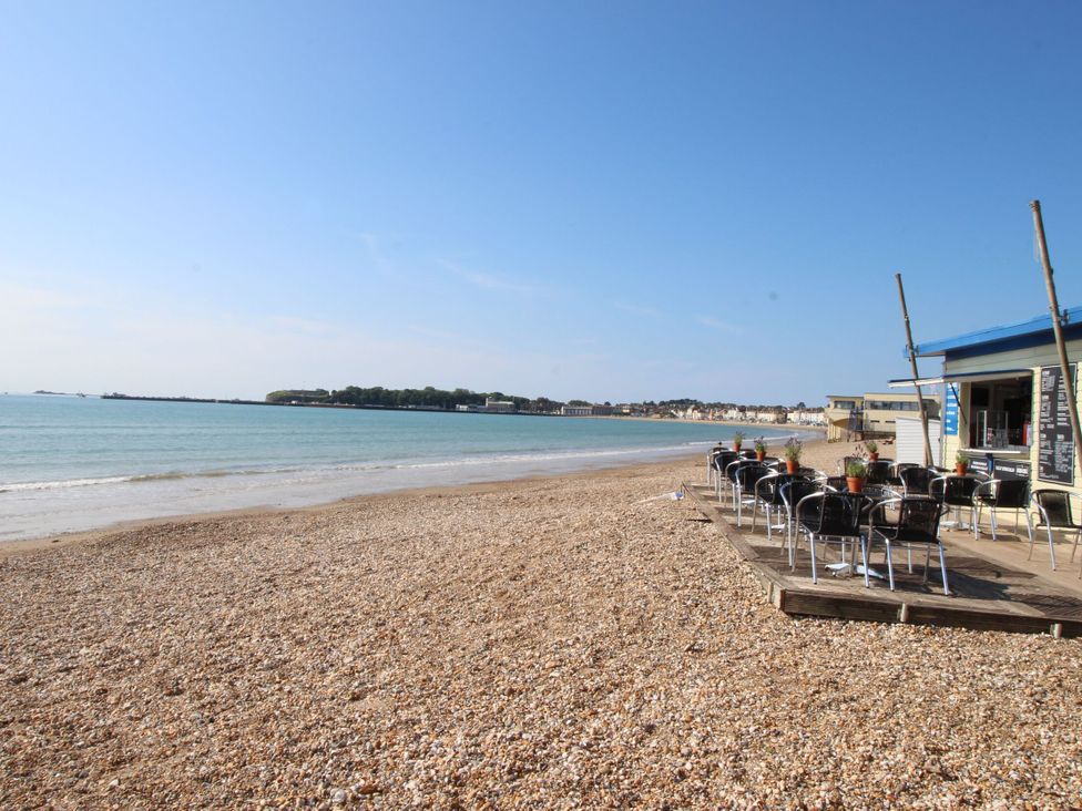 A beach with a restaurant and chairs at Mayflower Cottage in Lyme Regis