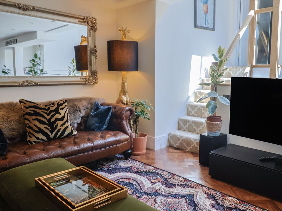 A living room with a sofa, a lamp, and a TV at Mayflower Cottage in Lyme Regis